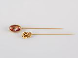 a pair of gold tone hair pins with a red stone