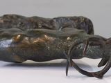 a bronze sculpture of a cow laying down on a white surface