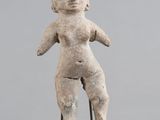 une petite statue représentant une femme tenant un bébé dans ses bras, posée sur un socle noir