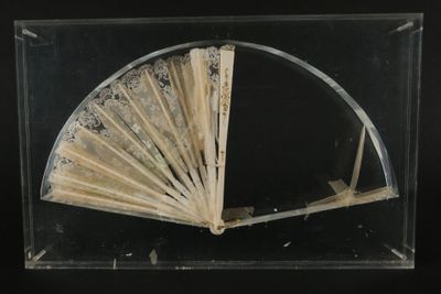 un vieux ventilateur dans une vitrine, posé sur un socle noir