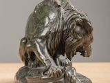 bronze statue of a lion on a rock on a wooden table