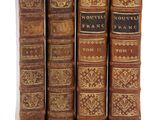 quatre vieux livres sont alignés sur une surface blanche