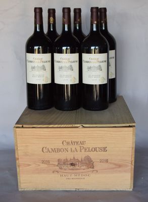 four bottles of red wine in a wooden box on a table