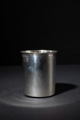 an empty silver cup on a dark surface with a black background