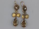 a pair of earrings with leaves and pearls on them
