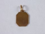 a close up of a gold plated pendant on a white surface