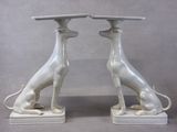 pair of white ceramic greyhounds sitting on pedestals on grey background