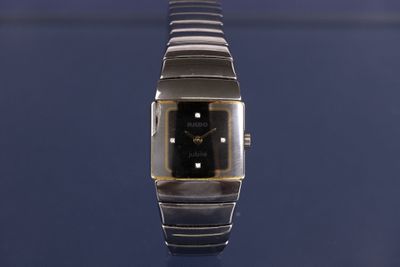 un gros plan d'une montre posée sur une surface bleue
