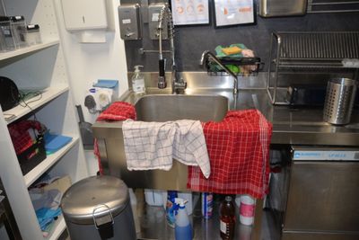 a kitchen with a sink, a trash can, and a trash can
