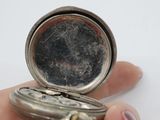 a person holding a silver pocket watch in their hand