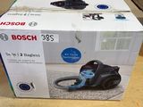 un carton contenant un aspirateur posé par terre devant une fenêtre