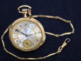 a gold pocket watch on a chain on a black surface