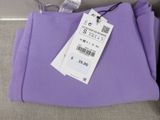 a purple shirt with a price tag on it sitting on a couch