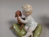 a figurine of a boy sitting on a leaf with a dog