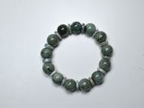 un bracelet composé de perles de jade vert sur un fond blanc