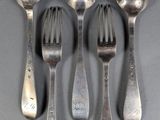 five silver spoons and a fork on a gray surface