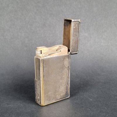 a silver lighter with a metal case sitting on top of a table