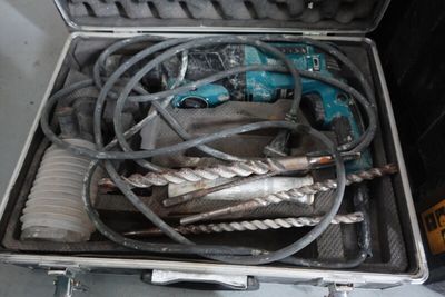 une mallette métallique posée par terre, contenant des outils