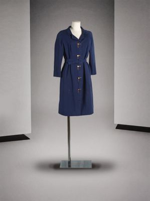 un manteau bleu posé sur un pied de mannequin dans une pièce