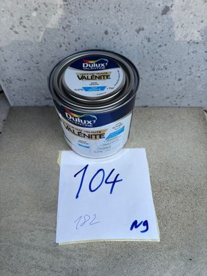 un pot de peinture posé sur un sol en béton, à côté d'un panneau