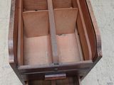 une petite boîte en bois avec des tiroirs, posée par terre