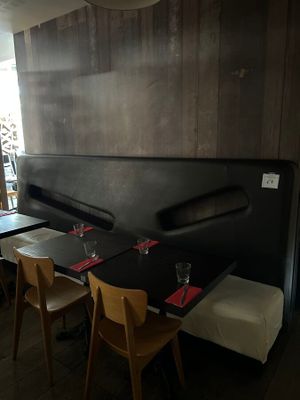 tables and chairs in a restaurant with wooden walls and a black bench
