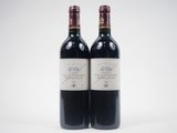two bottles of red wine sitting next to each other on a white surface