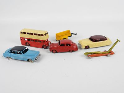 quatre petites voitures et un bus posés sur une surface blanche