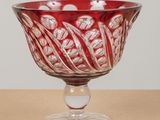 a red glass bowl sitting on top of a wooden table