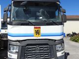 un camion blanc orné d'une bande bleue, garé sur un parking