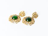 une paire de boucles d'oreilles vertes et dorées sur fond blanc