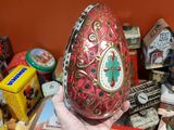 a person holding an egg in front of a pile of tins