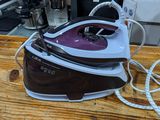 a brown and white steam iron sitting on a wooden table