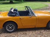 a small yellow car parked in a gravel lot