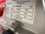 a close up of a meat mincerer with a basket in the background