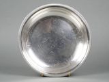 a silver plate on a stand on a gray surface