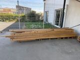 Plusieurs morceaux de bois sont empilés sur des palettes devant un bâtiment