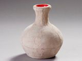 un vase blanc surmonté d'un couvercle rouge, posé sur une table