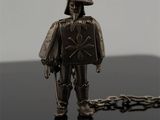 une figurine en argent représentant un homme coiffé d'un chapeau et tenant une épée