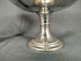 a silver bowl on a stand on a black background