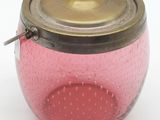 un bocal en verre rose avec un couvercle en laiton