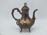 an antique silver tea pot with a handle on a stand