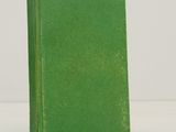 un vieux livre vert posé sur une table blanche
