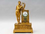 une statue en or représentant une femme tenant une harpe et une horloge