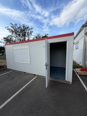 a small white building with a red roof in a parking lot