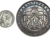 une vieille pièce d'argent surmontée d'une couronne, à côté d'une pièce sur laquelle figure une couronne