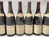 six bouteilles de vin sont alignées sur une table