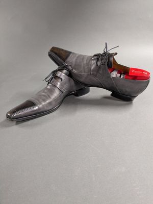 men ' s gray leather shoes with red soles on a grey background