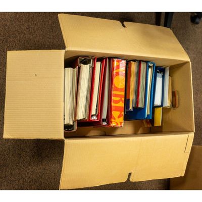 a box full of books sitting on the floor next to a chair