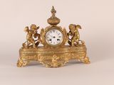 une horloge en or ornée d'anges, posée sur une table